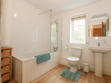 A bathroom with a bathtub shower toilet sink and window at The Mill Stones in Stalham