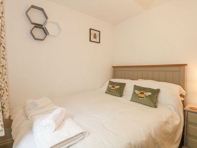A bedroom with a bed and bee-themed pillows and artwork at The Mill Stones in Stalham