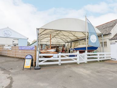 An outdoor covered area with wooden boats and a white fence at the Museum of the Broads in Stalham