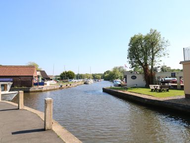 A canal with boats docked along the sides and buildings near the water at The Mill Stones in Stalham