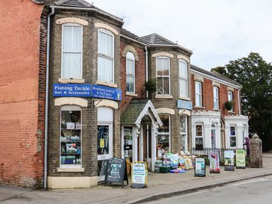 A fishing tackle and pet centre shop with signs and products outside on a street at The Mill Stones in Stalham