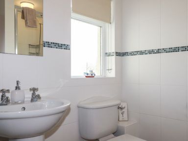 A bathroom with a sink mirror toilet and tiled walls at Freefolk Cottage in Polzeath