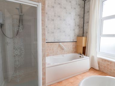 A bathroom with a shower enclosure bathtub window and wooden flooring at Promenade in Bridlington