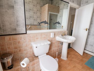 A bathroom with a toilet sink mirror and tiled walls at Promenade in Bridlington