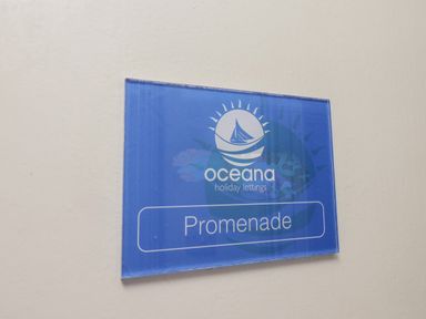 A blue sign with a sailboat logo and text oceana holiday lettings Promenade