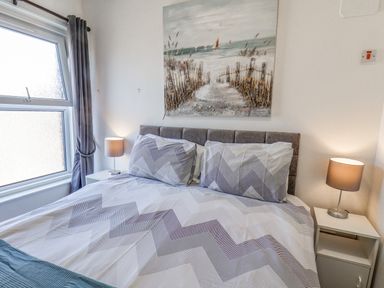 A bedroom with a double bed two bedside tables with lamps and a window at Ocean Wave in Bridlington