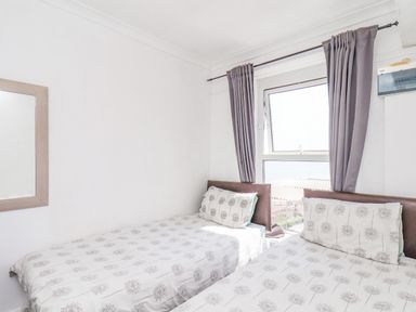 A bedroom with two single beds next to a window with gray curtains and a wall mirror at Ocean Wave in Bridlington