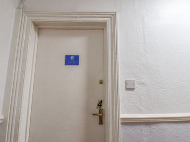 A closed door with a blue Ocean Wave sign and number 4 on the handle in a white hallway at Ocean Wave in Bridlington