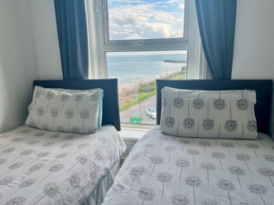 A bedroom with two single beds by a window with a view of the sea at Ocean Wave in Bridlington