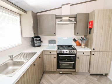 A kitchen with a gas stove oven sink air fryer and utensils at Beechwood Lodge in Hasguard Cross near Broad Haven