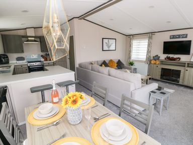 A kitchen and living room with a dining table set with plates and flowers at Beechwood Lodge Hasguard Cross near Broad Haven