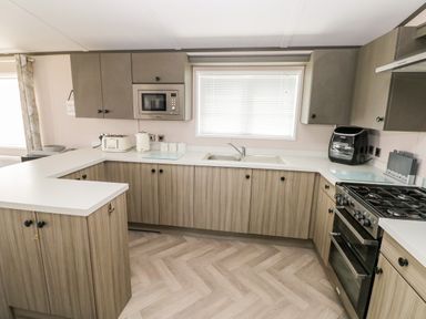 A kitchen with wood cabinets a microwave toaster kettle air fryer stove and a window with blinds at Beechwood Lodge in Hasguard Cross near Broad Haven