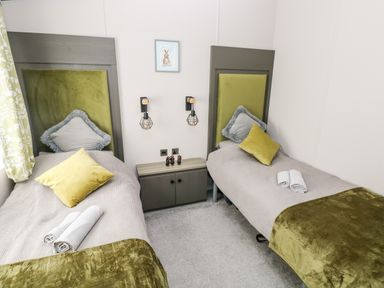 A bedroom with two single beds and a cabinet between them at Beechwood Lodge in Hasguard Cross near Broad Haven