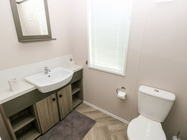 A bathroom with a sink cabinet mirror window and toilet at Beechwood Lodge in Hasguard Cross near Broad Haven