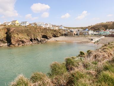 A coastal village with houses on cliffs and a beach by a bay at Beechwood Lodge in Hasguard Cross near Broad Haven
