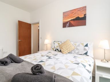 A bedroom with a bed with patterned bedding two bedside tables with lamps and a wall photo at 3 Seaview Bridlington Bay in Bridlington