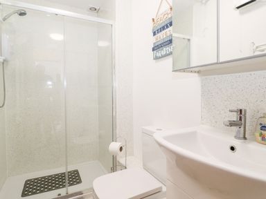 A bathroom with a shower enclosure toilet sink and a wall decoration at 3 Seaview @ Bridlington Bay in Bridlington
