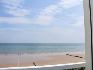 A beach with people walking near the water and wooden groynes at 4 Seaview @ Bridlington Bay in Bridlington