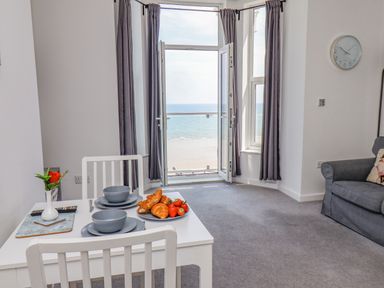 A dining area with a table set for two facing a window with a sea view at 4 Seaview @ Bridlington Bay in Bridlington