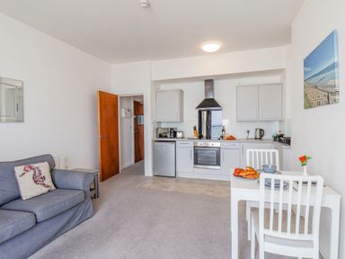 A kitchen and living area with a grey sofa and a white dining table at 4 Seaview Bridgeington Bay in Bridlington