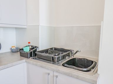 A kitchen corner with a dual sink and dish drying racks with cleaning items on the counter at 4 Seaview @ Bridlington Bay in Bridlington