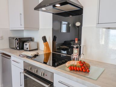 A kitchen counter with a stove toaster microwave bread tomatoes and wine at 4 Seaview @ Bridlington Bay in Bridlington