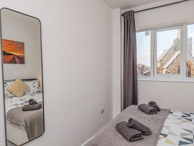 A bedroom with a bed covered with a blanket and towels next to a window with curtains at 4 Seaview @ Bridlington Bay in Bridlington