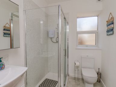 A bathroom with a shower enclosure, toilet, sink, and a frosted window at 4 Seaview Bridlington Bay in Bridlington