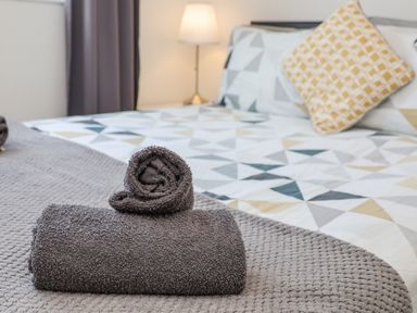 A bed with patterned bedding and folded towels on a textured blanket in a bedroom at 4 Seaview @ Bridlington Bay Bridlington