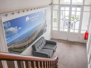 A hallway with a grey sofa large wall art and glass front doors at 4 Seaview at Bridlington Bay in Bridlington