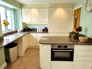 A kitchen with beige cabinets and countertops with a built in oven and a window with flowers on the sill at The Paddock in Keswick