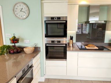 A kitchen with double ovens a stove with bread on it and a fruit basket on the counter at The Paddock in Keswick