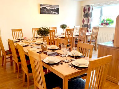 A dining room with wooden tables and chairs set with white plates glasses and cutlery at The Paddock in Keswick