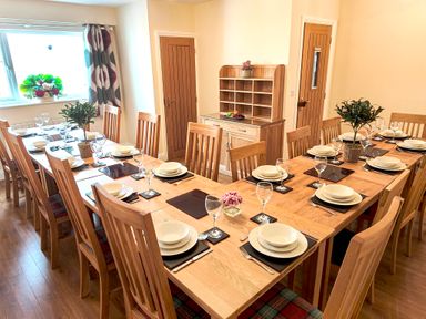 A dining room with wooden tables and chairs set with plates glasses and cutlery at The Paddock in Keswick