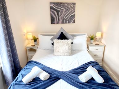 A bedroom with a double bed two bedside tables lamps and curtains at The Paddock in Keswick