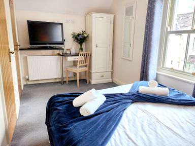 A bedroom with a bed, towels, a desk with a chair and a television at The Paddock in Keswick