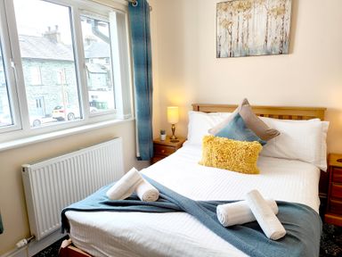 A bedroom with a bed pillows bedside tables and a window at The Paddock in Keswick