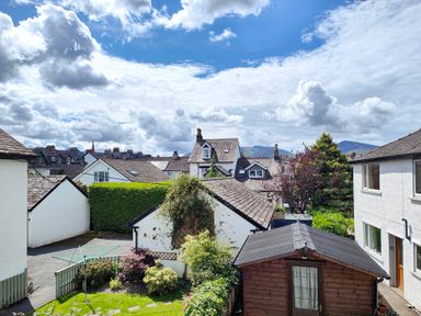 A view of residential houses with gardens and sheds under a partly cloudy sky at The Paddock in Keswick