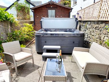 An outdoor patio with a hot tub garden furniture and a wooden shed at The Paddock in Keswick