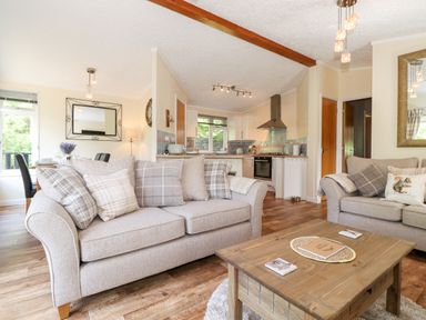 A living room with sofas and a wooden coffee table near an open kitchen at Nutkins Lodge in Beckside 5 Limefitt Park near Windermere