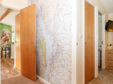 A hallway with two wooden doors and a wall covered by a large map at Nutkins Lodge Beckside 5 Limefitt Park near Windermere