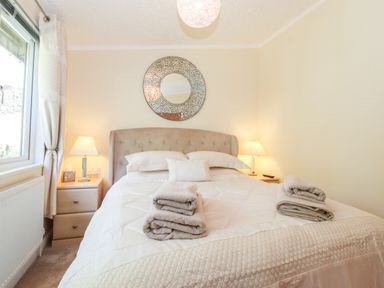 A bedroom with a double bed and bedside tables with lamps at Nutkins Lodge in Beckside 5 Limefitt Park near Windermere