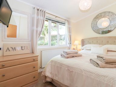 A bedroom with a bed folded towels a chest of drawers and a window at Nutkins Lodge Beckside 5 Limefitt Park near Windermere