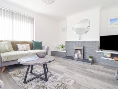 A living room with a sofa cushions coffee table and a TV near a fireplace at Apple Tree Bungalow in Lanner