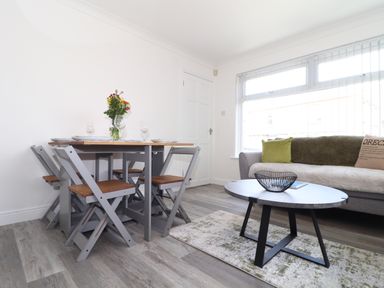 A dining area with a table set for four and a living area with a sofa and coffee table at Apple Tree Bungalow in Lanner