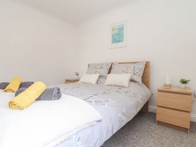 A bedroom with a bed covered in floral bedding and two bedside tables with plants at Apple Tree Bungalow in Lanner