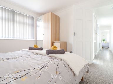 A bedroom with a bed covered in a floral duvet a wooden wardrobe and a chest of drawers at Apple Tree Bungalow in Lanner