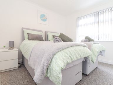 A bedroom with two single beds with green patterned bedding and a nightstand with a lamp at Apple Tree Bungalow in Lanner