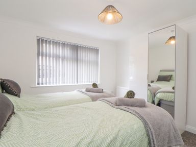 A bedroom with two single beds a window with vertical blinds and a wardrobe with a mirrored door at Apple Tree Bungalow in Lanner