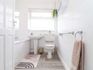 A bathroom with a toilet sink and bathtub with a towel hanging on a ring at Apple Tree Bungalow in Lanner